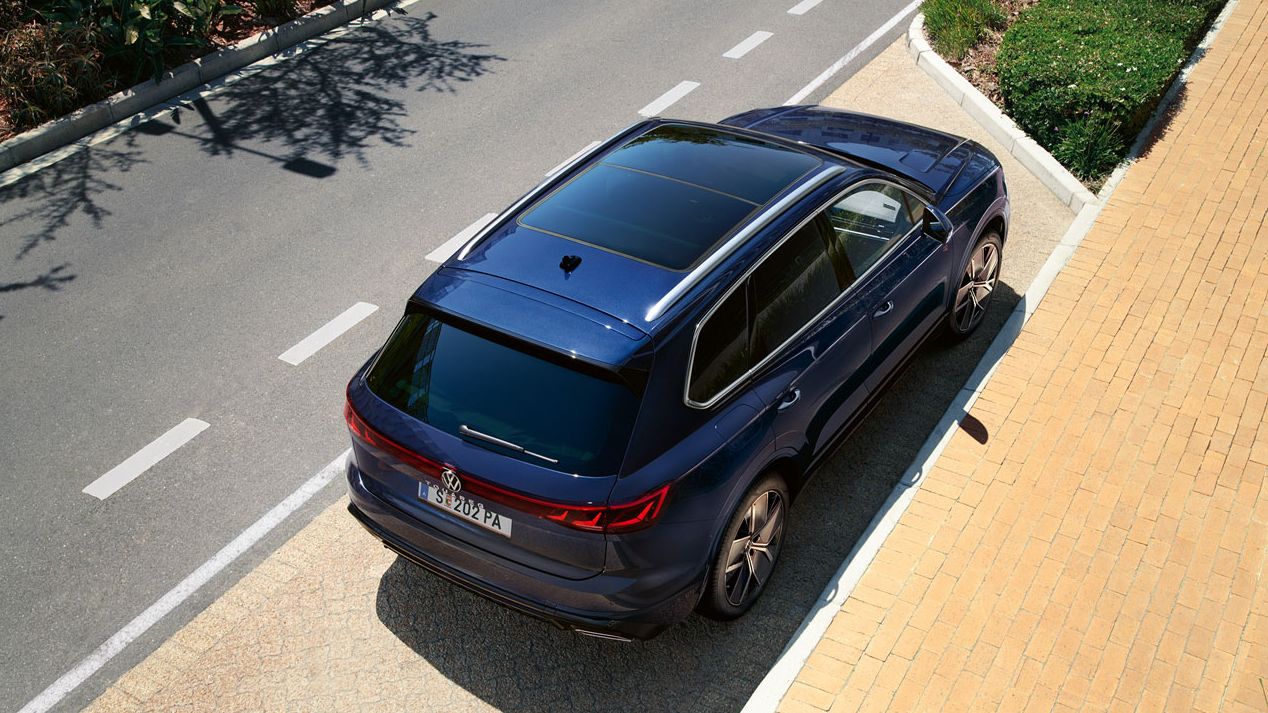 Ein VW Touareg R-Line parkt am Straßenrand, Ansicht von schräg oben auf das Heck und Panoramaglasdach.