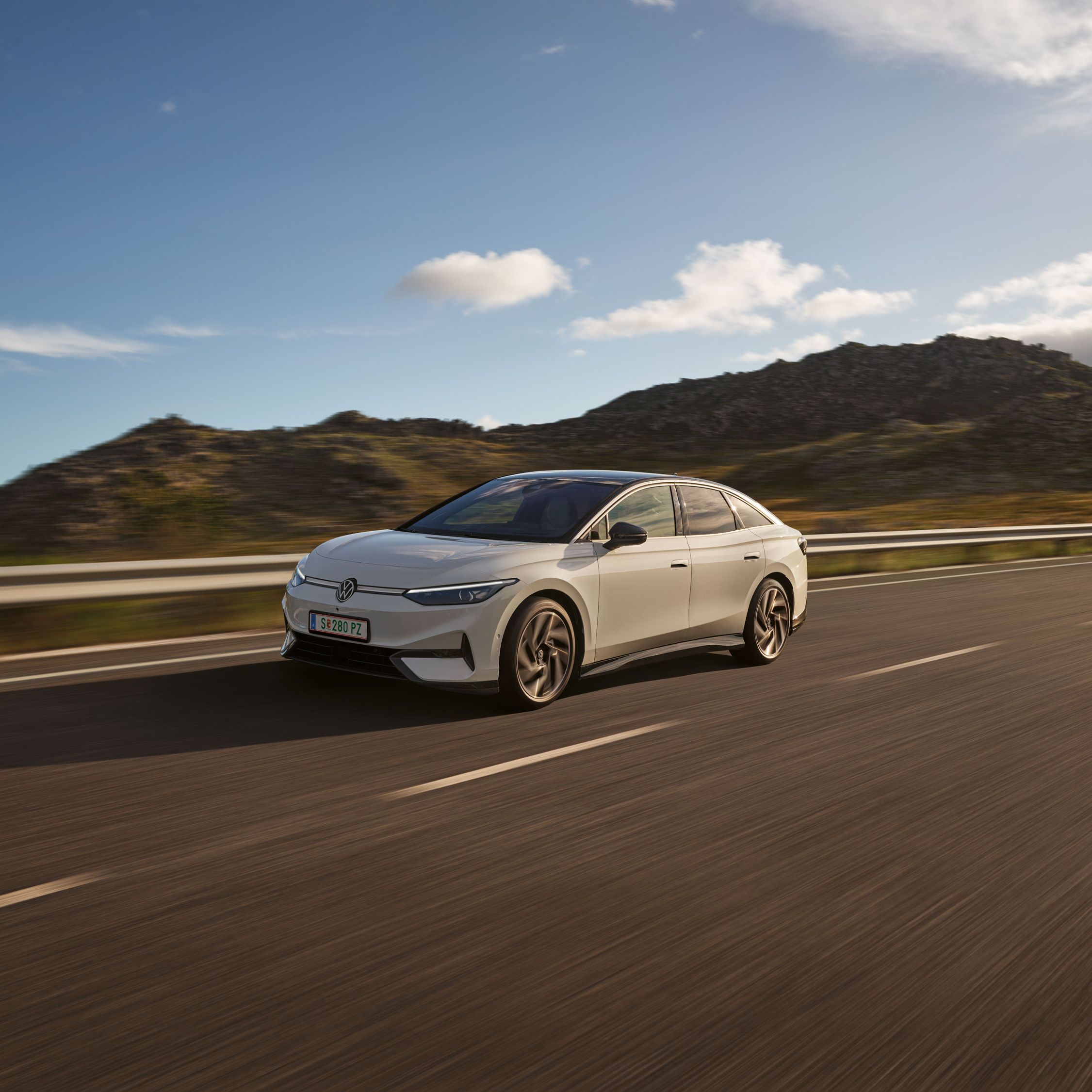 VW ID.7 fährt auf einer Landstraße, Blick auf die aerodynamisch gestaltete Front.