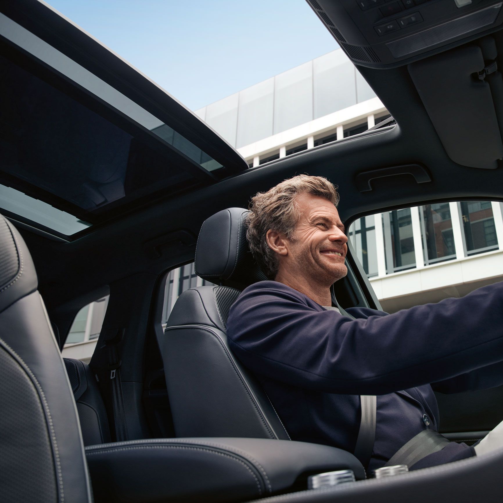 Blick durch das Panoramadach des VW Touareg, ein Mann sitzt am Steuer