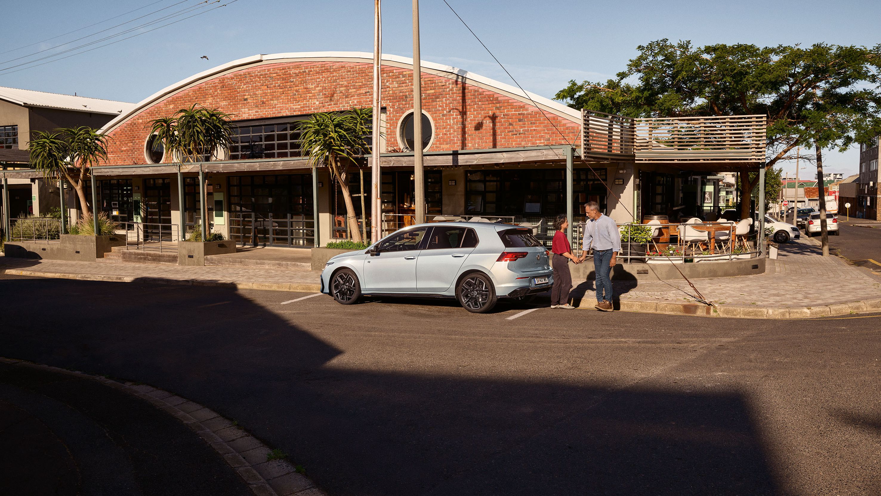 Der neue Golf GTE parkt an einem Straßenrand neben einem Café.
