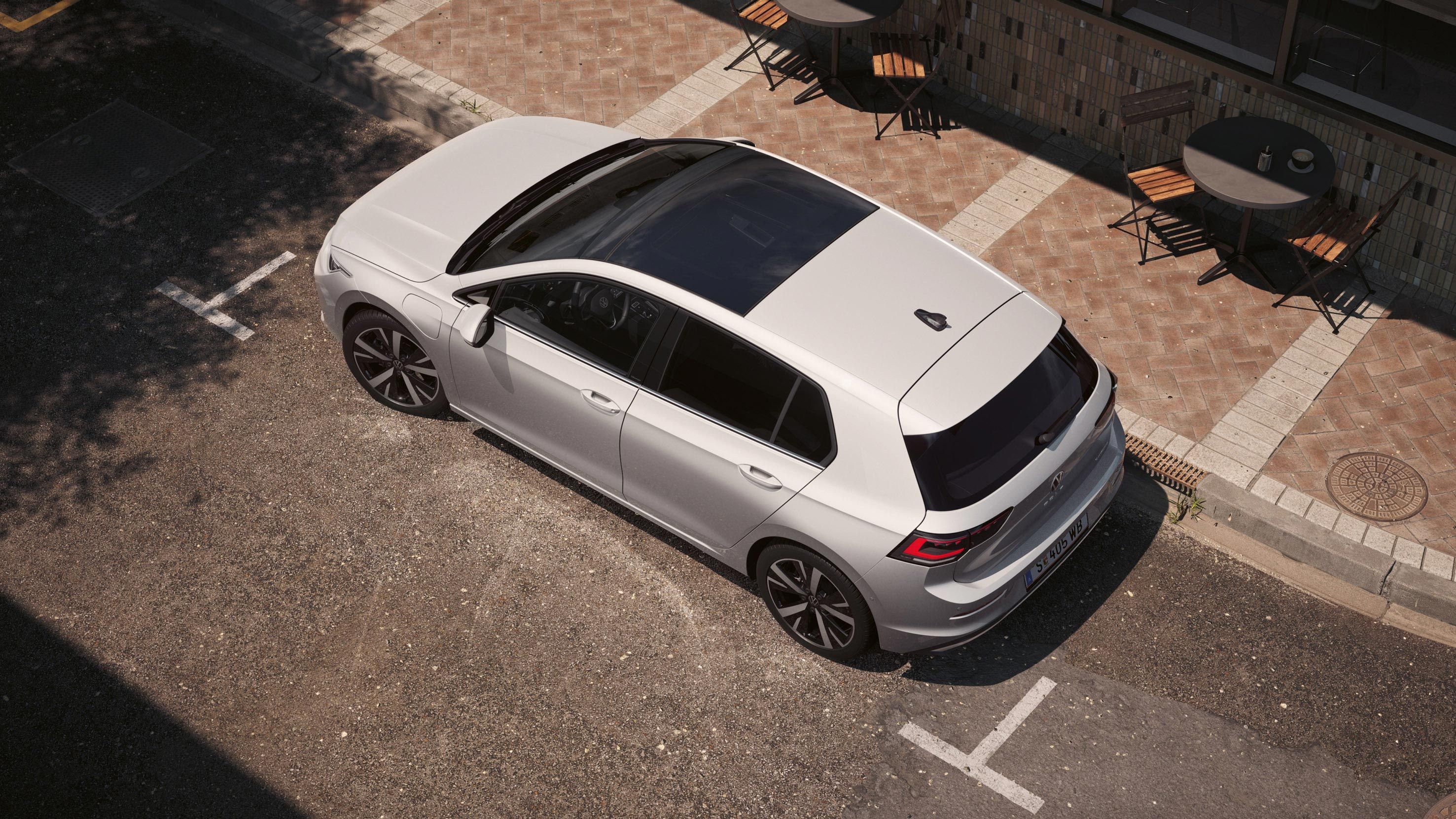 Ein weißer VW Golf eHybrid mit Panoramadach aus der Vogelperspektive, von oben