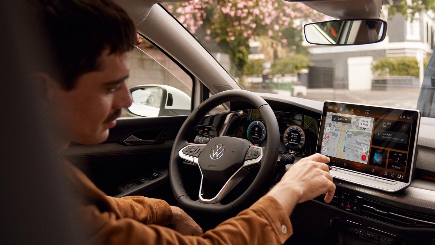 Man bedient Touchscreen des Infotainmentsystems im VW Golf