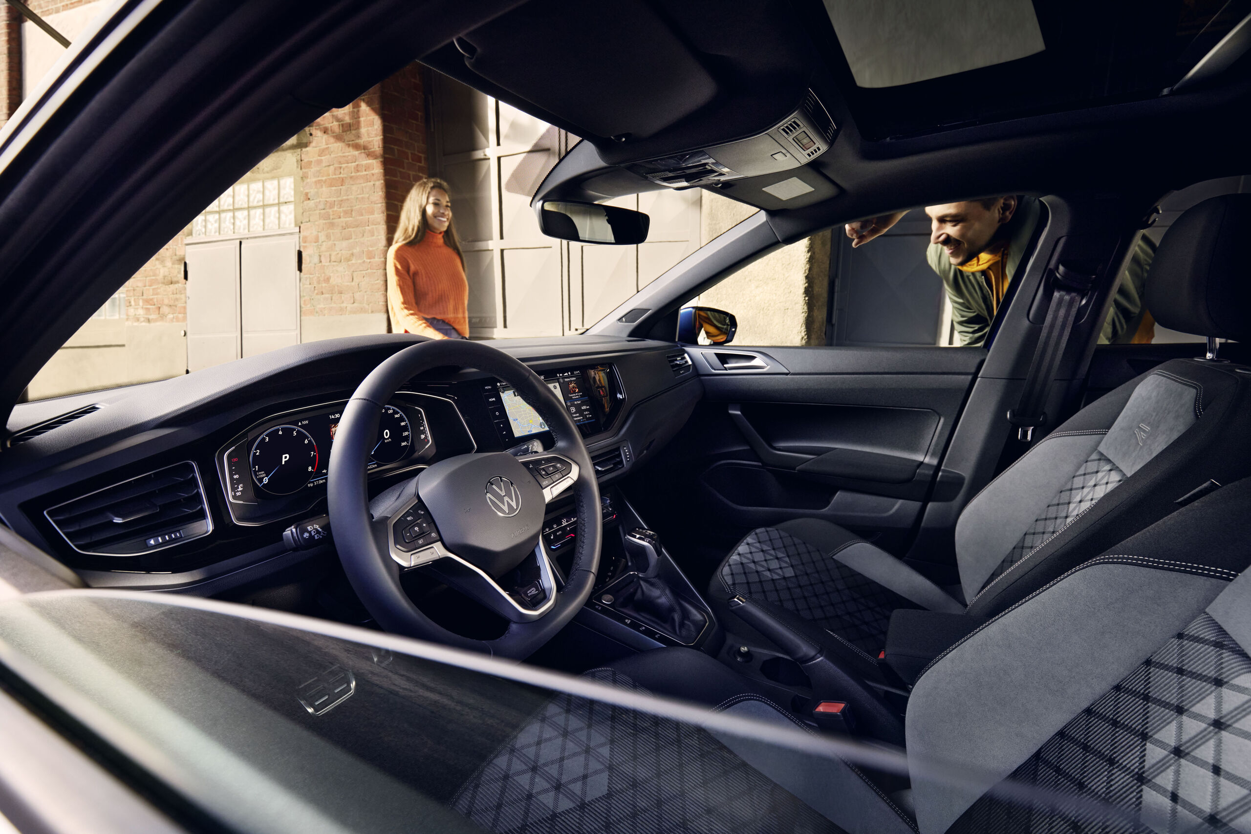 Blick durch die heruntergelassene Scheibe quer durch den Innenraum des VW Polo mit optionalem Digital Cockpit Pro, Lenkrad und Sitzen. 