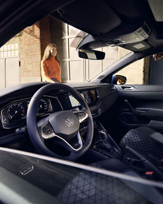 Blick durch die heruntergelassene Scheibe quer durch den Innenraum des VW Polo mit optionalem Digital Cockpit Pro, Lenkrad und Sitzen. 