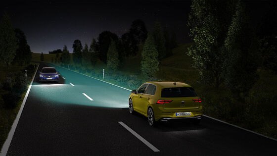 Ein VW Golf uf einer Landstraße, der Lichtkegel wird für ein entgegenkommendes Fahrzeug verkleinert
